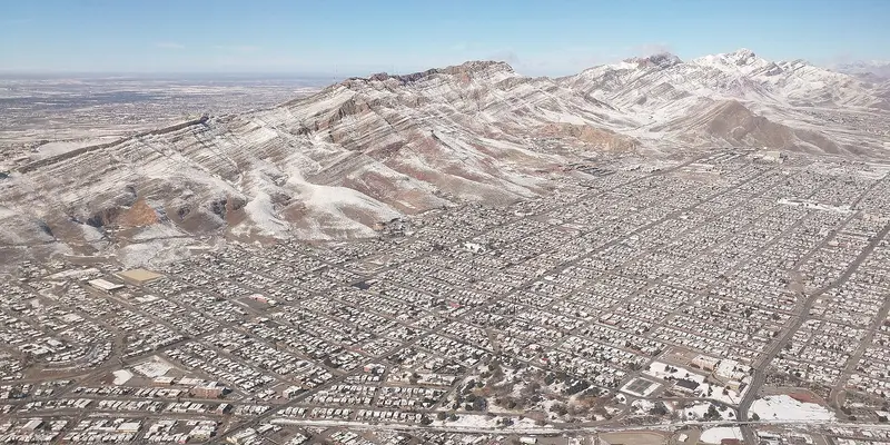 Aerial view of West El Paso neighborhoods below the snow-dusted Franklin Mountains.